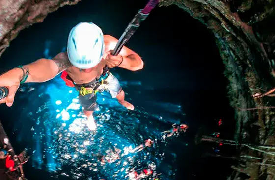 Visitante haciendo un salto controlado hacia un cenote