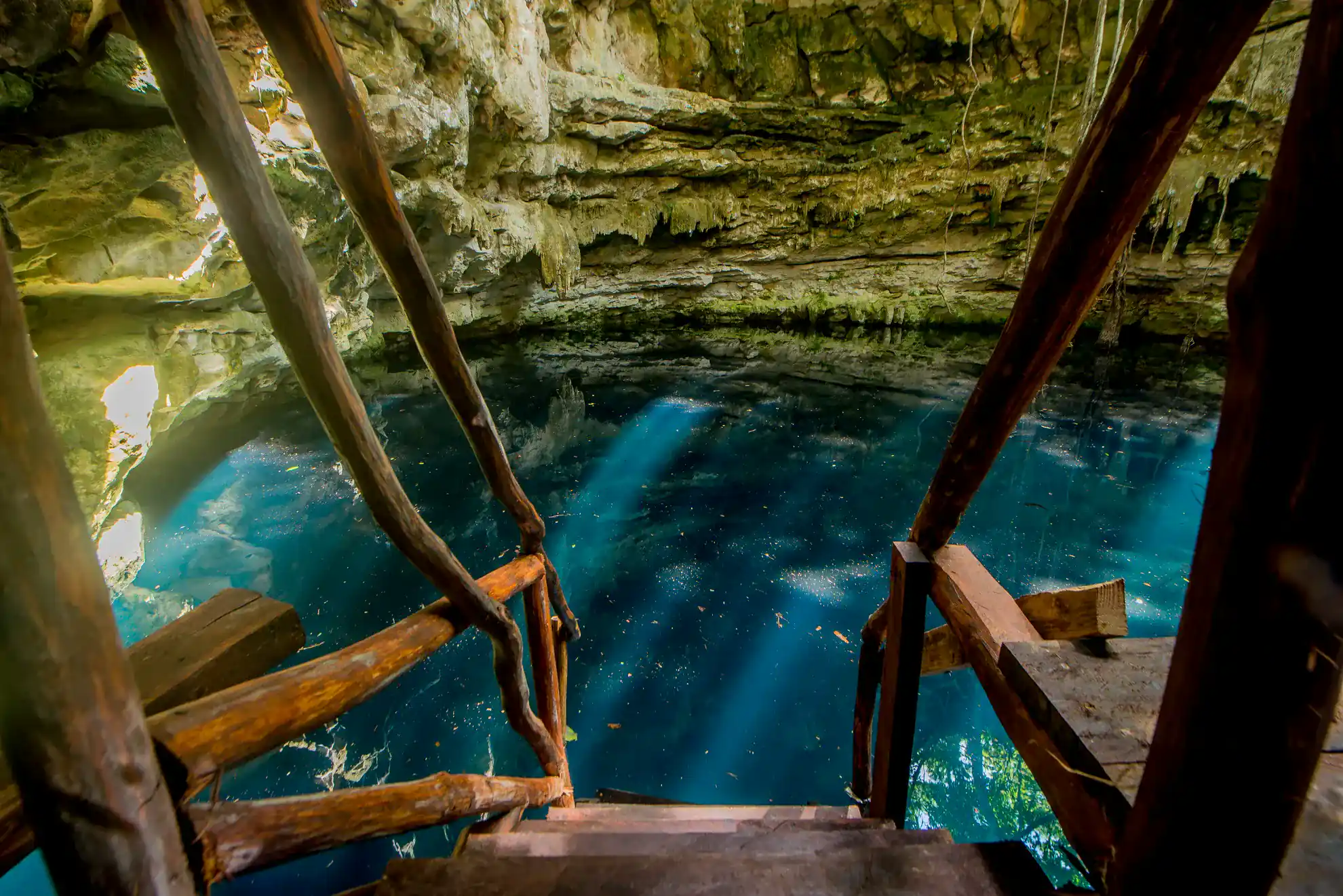 Escalones de piedra que conducen a un cenote de agua azul